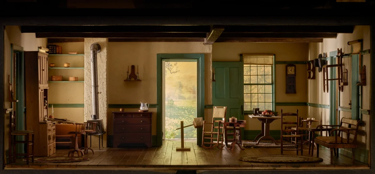 Miniature Shaker room with wooden chairs, a stove, pegged wall storage and an open door